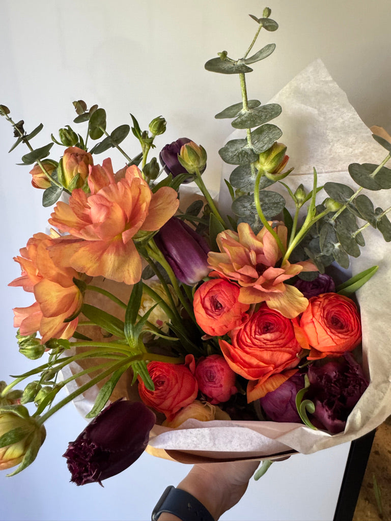 Bouquet of flowers held by a person with a neutral background
